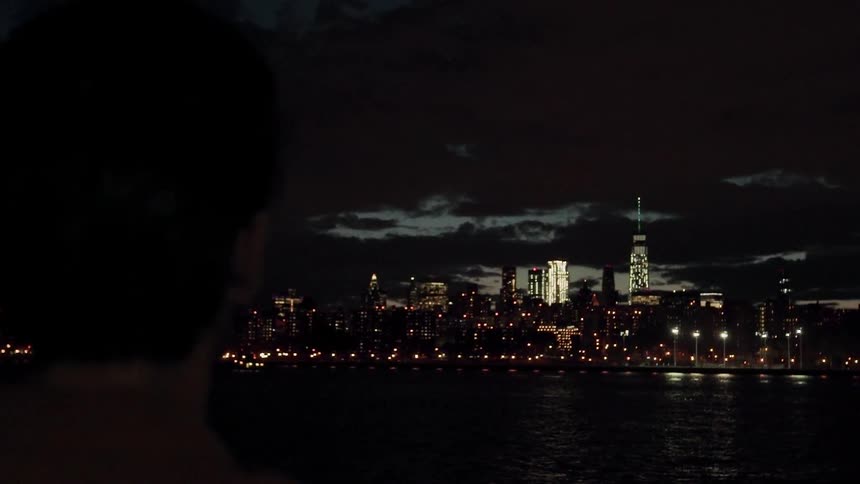 Someone is looking out over a river towards the lights of a big city