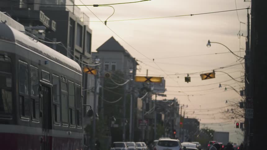 A busy city street has a trolly going down the middle of it