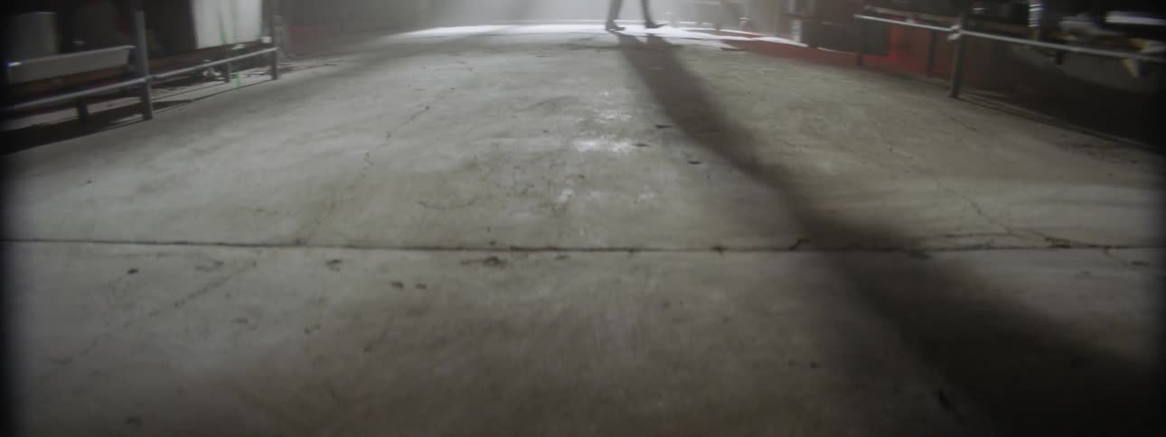 Person casts a shadow while walking across a concrete floor