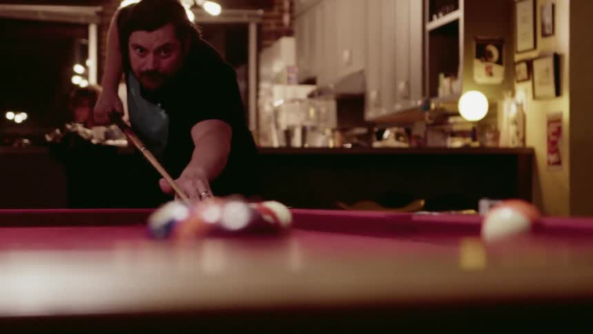 Man hits a billiard ball with a pool cue
