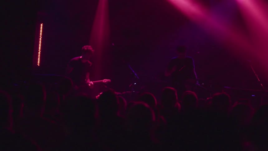 A large crowd is watching a band play on stage