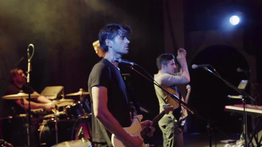 Band on stage playing instruments and clapping at concert
