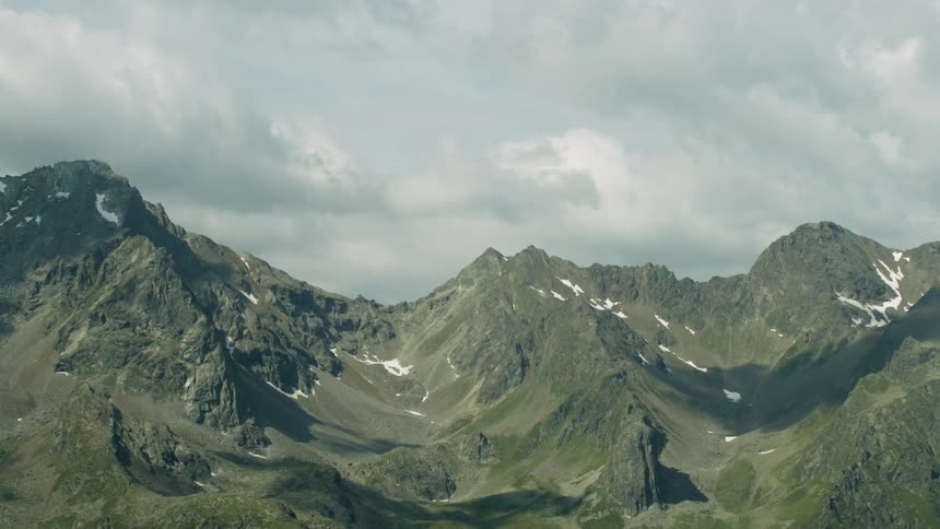 The long mountain range has heavy clouds above