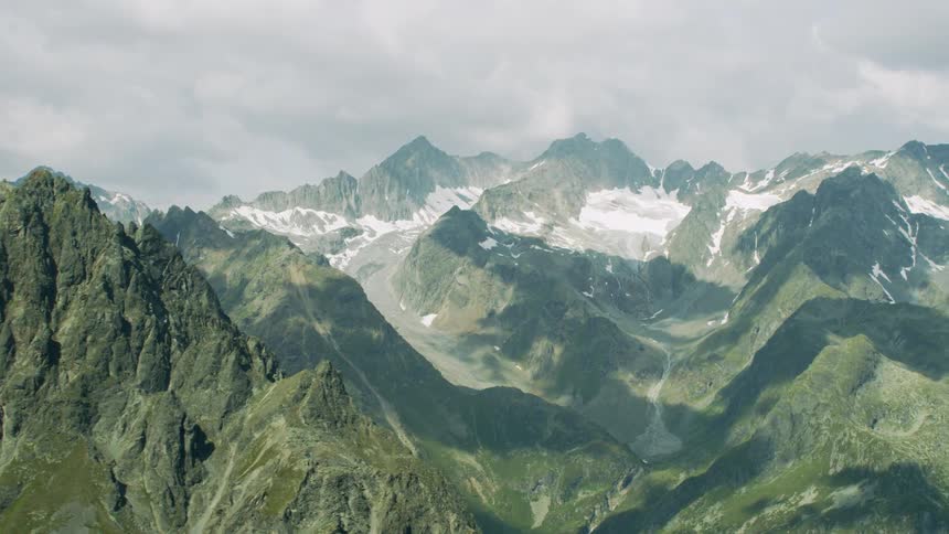 Snow covers the top of mountains on a cloudy day