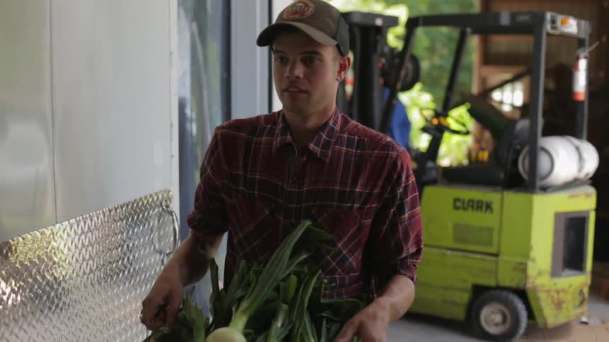 A guy carries a basket full of onions
