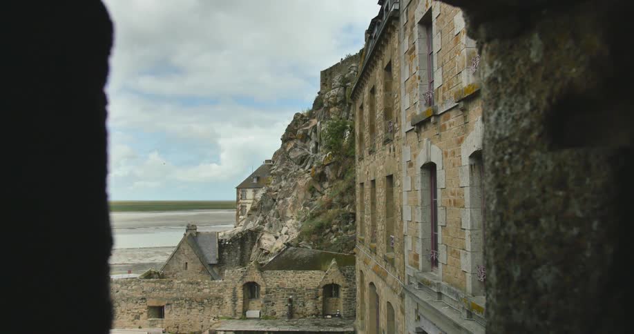 A view of the ocean from between two buildings located next to a cliff