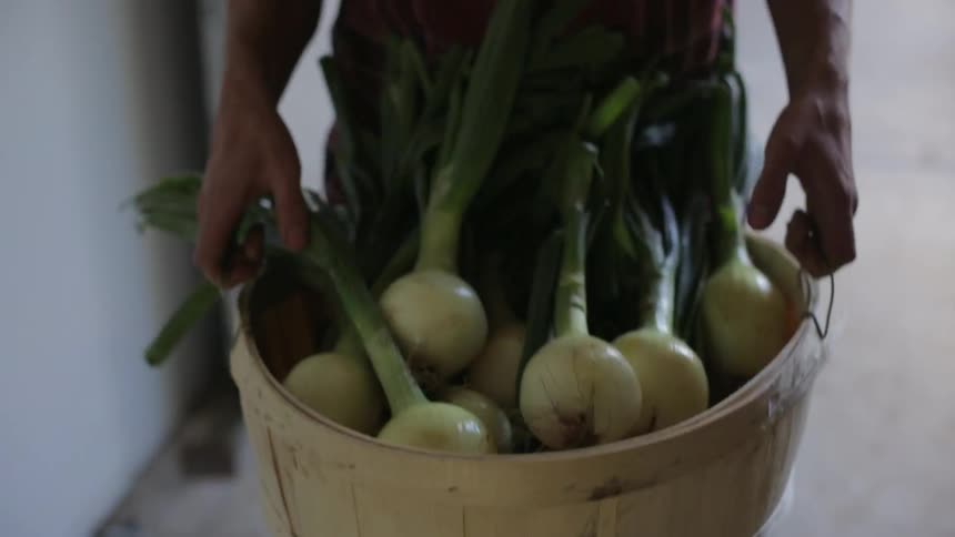 A man carries a heavy bushel of onions