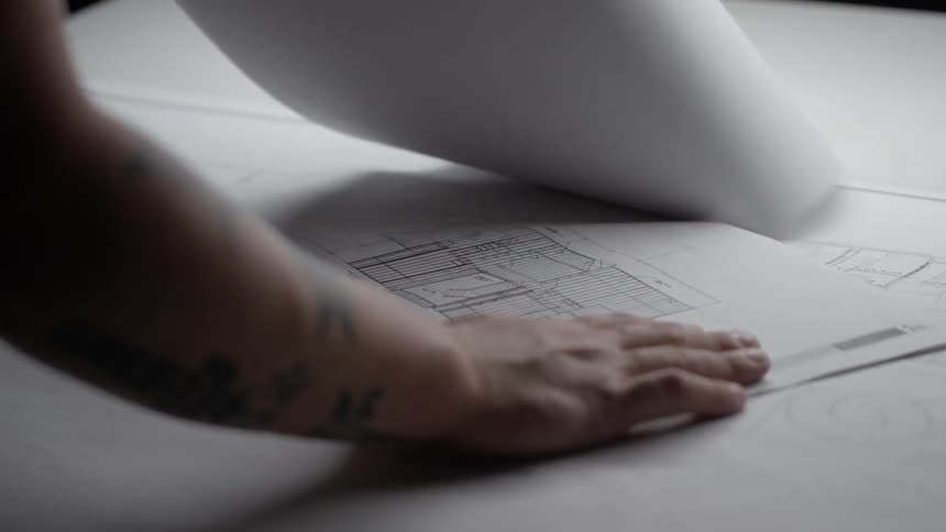 A person flips the page down of a blueprint
