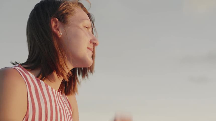 A woman smiles and looks forward on a windy day