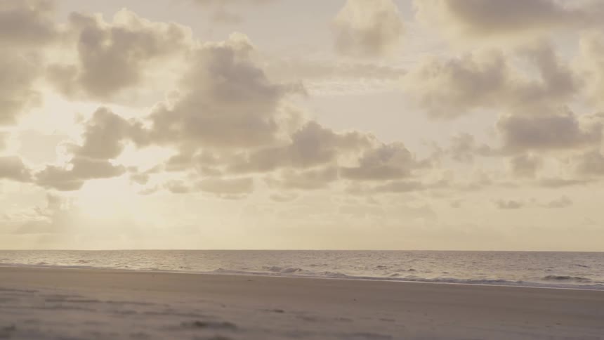 Waves come to shore on a sandy beach at sunset