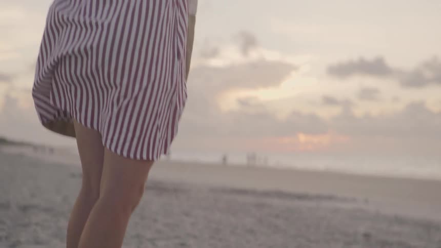 Woman walks onto a sandy beach at sunrise