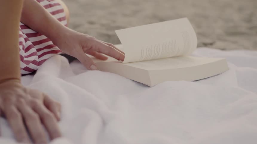 Woman sits on a blanket reading