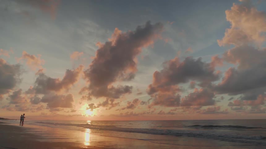 Two Men Fishing On The Beach At Sunrise
