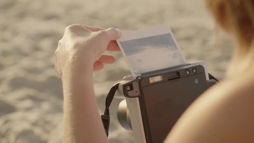 A woman takes a photograph on the beach