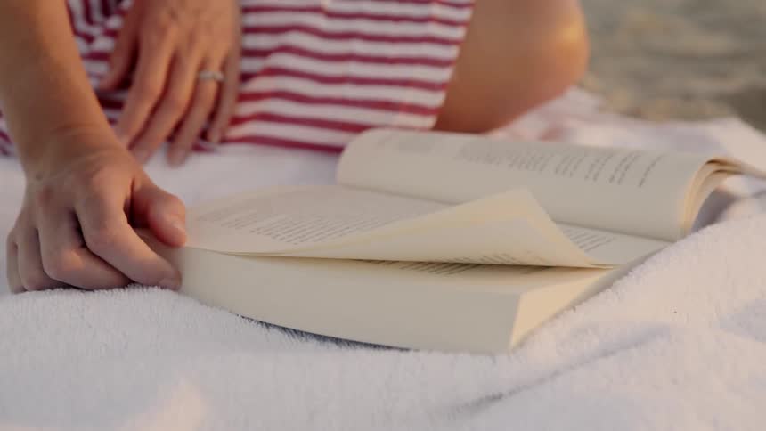 A woman reads a book on the beach