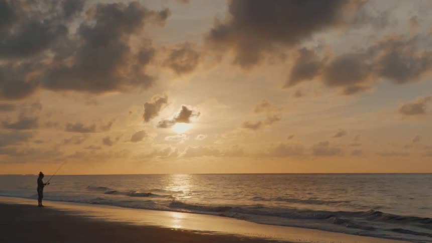 Man Fishing On The Beach At Sunrise