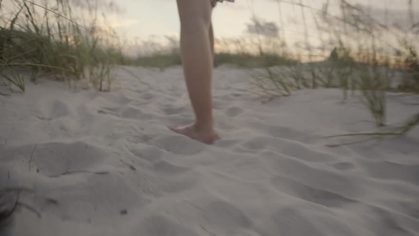 A woman walks on the sand