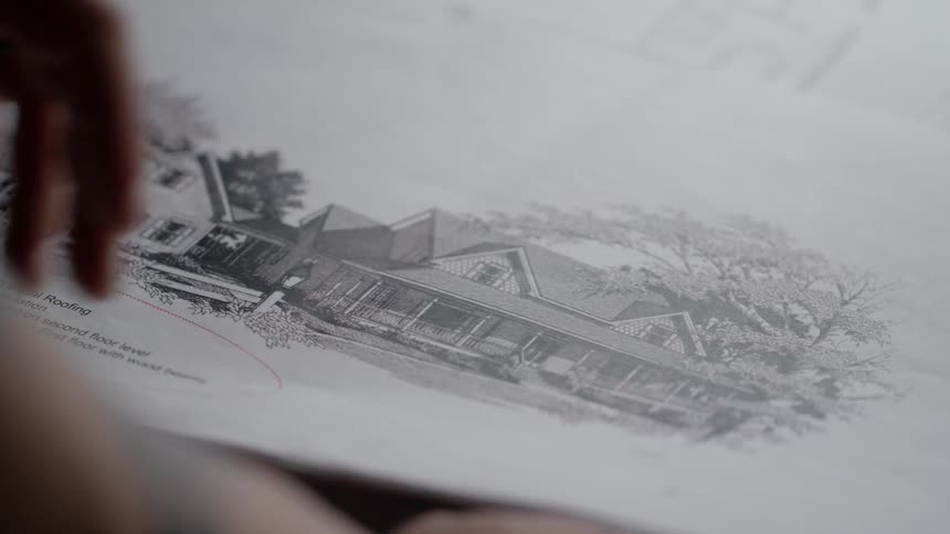 A man looks over blueprints on a table