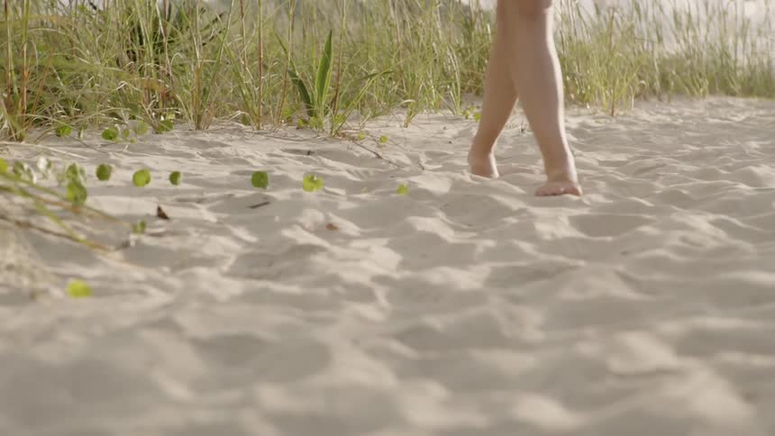 Woman walking through sand on sunny day