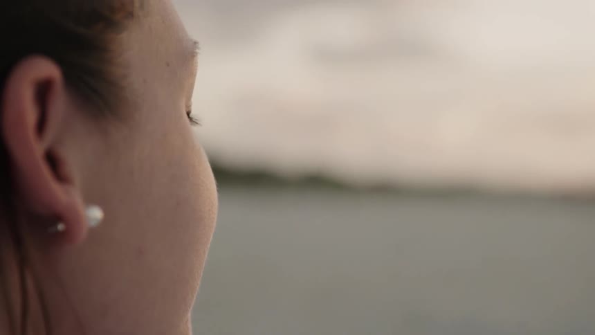 A woman stands outside at sunset