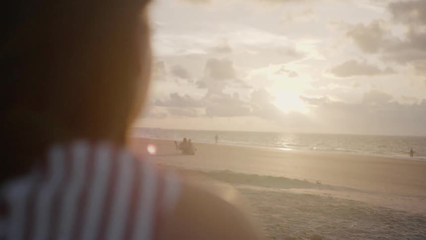 Woman looks out at the ocean at sunset
