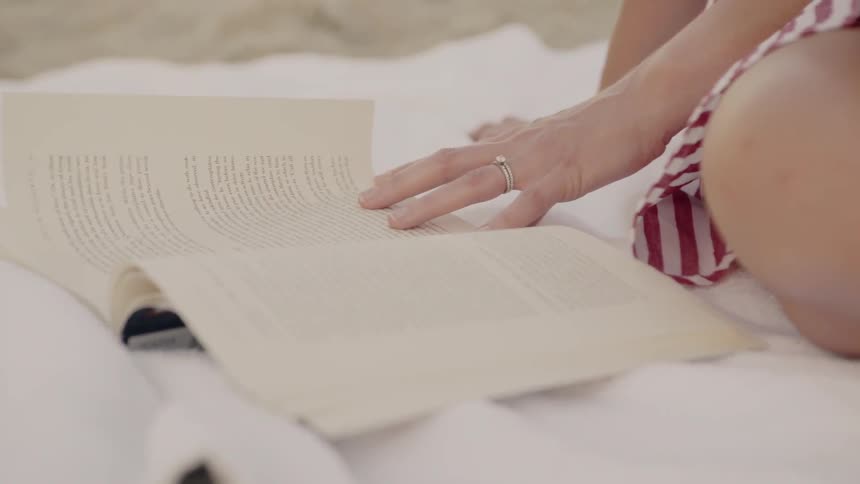 A woman reads a book at the beach