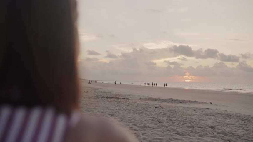 A woman is watching the waves crash against the shore