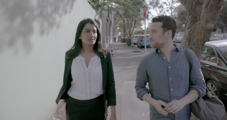 A man and woman walk down the city sidewalk