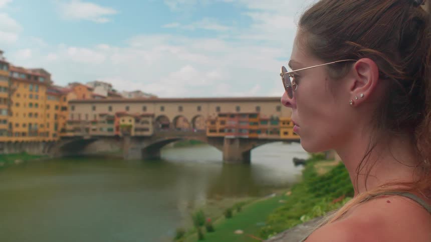 Woman standing near city water canal is staring at surroundings