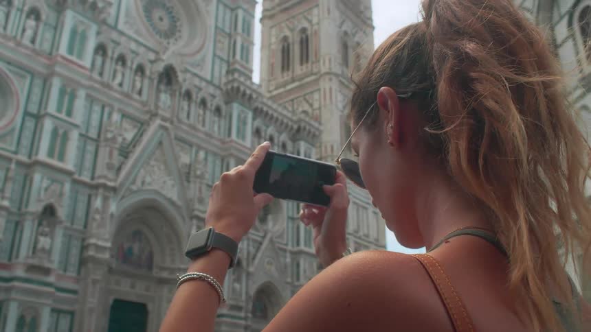 A woman is taking photos of a building on a windy day