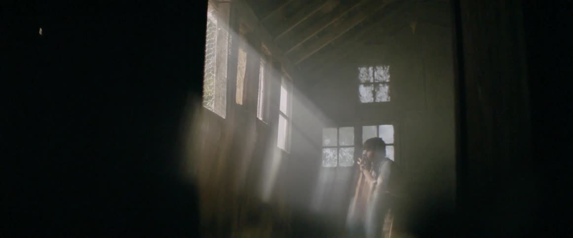 A person is sitting down in the dark room by the window