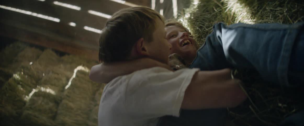 Two boys playing on bales of hay
