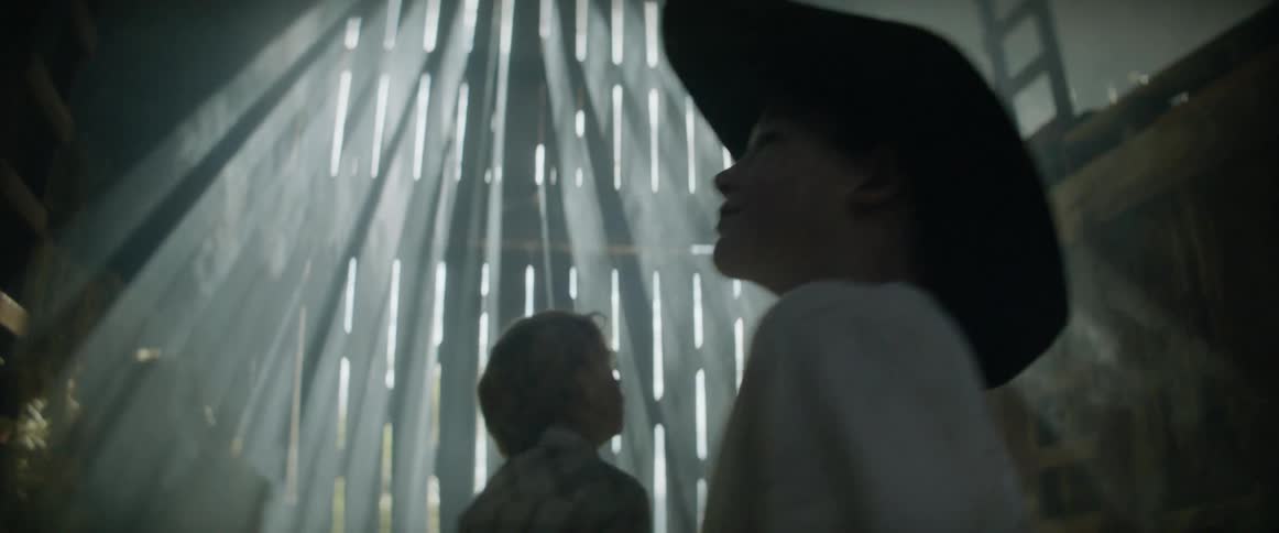 Two boys look around a barn as sunlight streams in