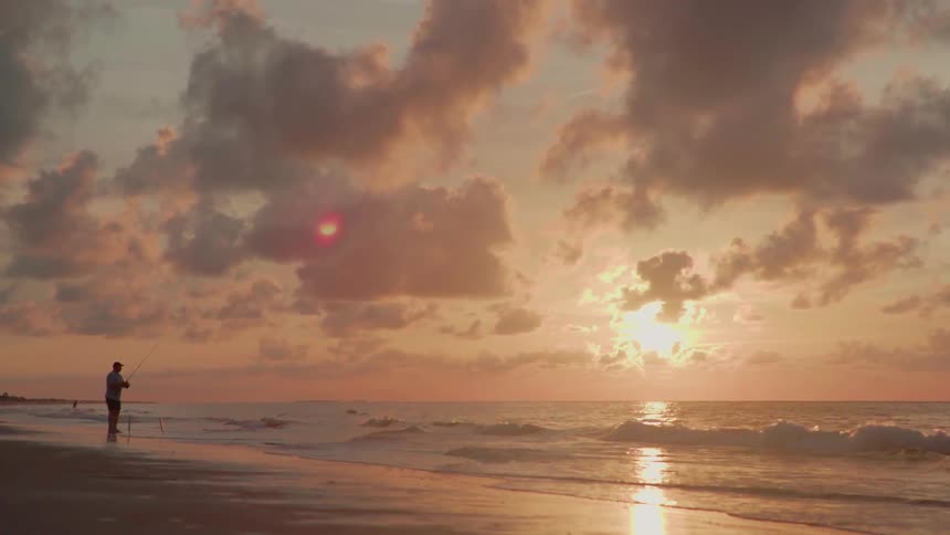 A man walks from the water at sunset