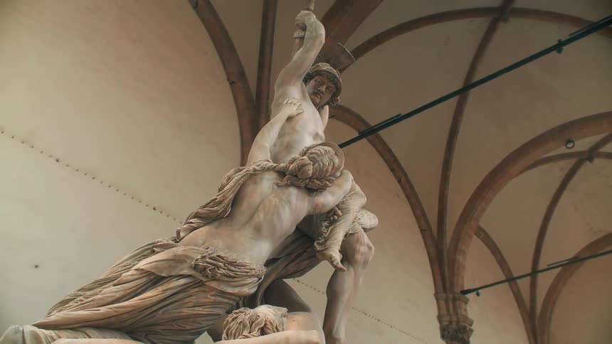 A statue of two people sit in front of this building
