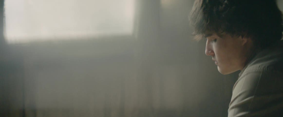 A man looks down sad by the window