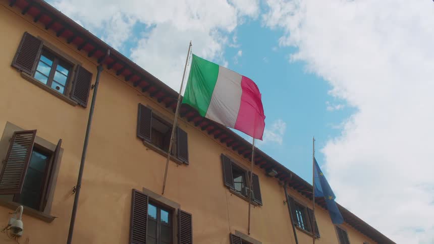 An italian flag hangs from the side of a building