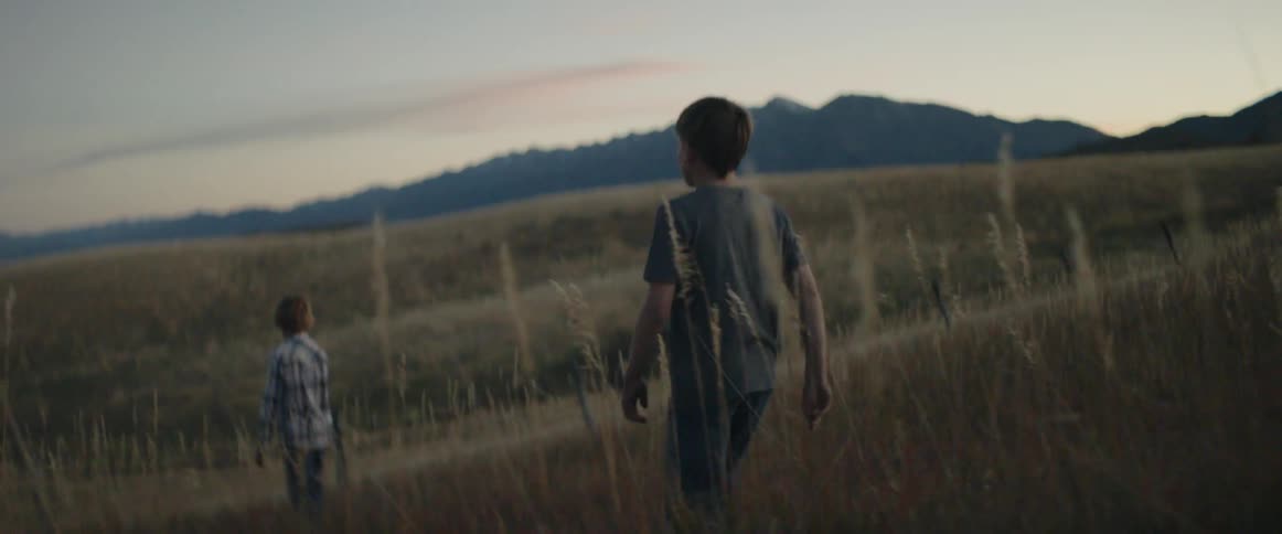 Boys walk down a grassy hill