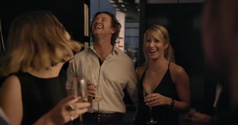 A group of friends are standing around drinking and laughing
