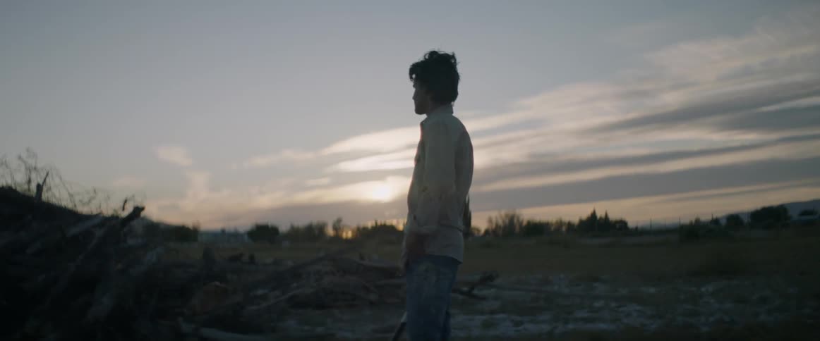 A man stands on the field watching the sunset