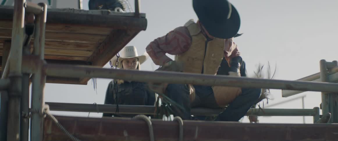 A rodeo rider gets on the bull in the cage
