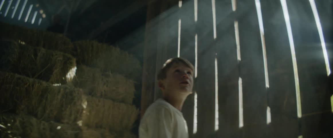 Two children walk past a long wooden barn door