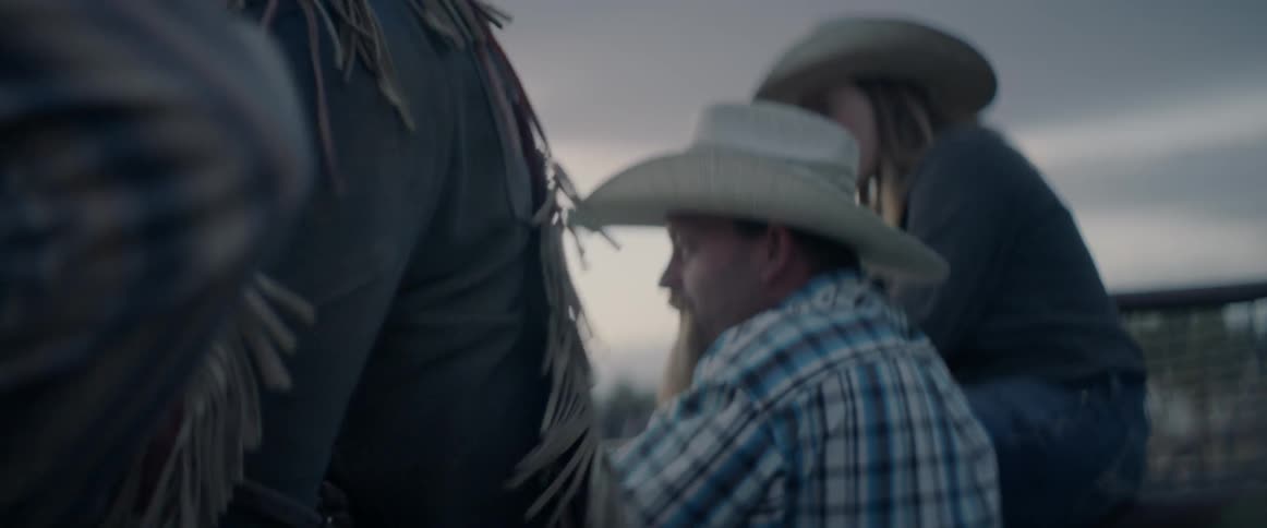 A man in a cowboy hat sits on a bull while others watch