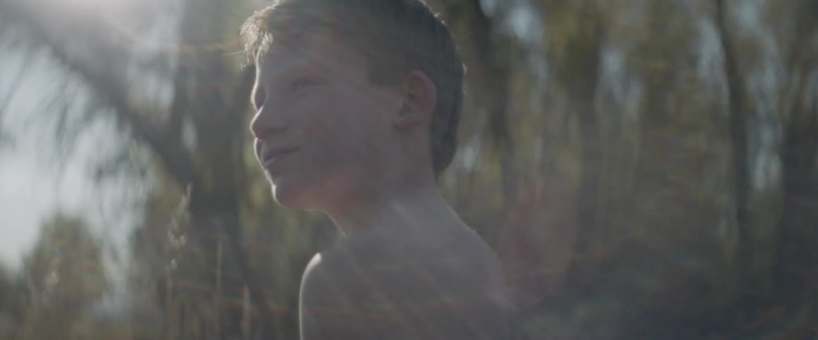 A boy removes his cowboy hat under the sun
