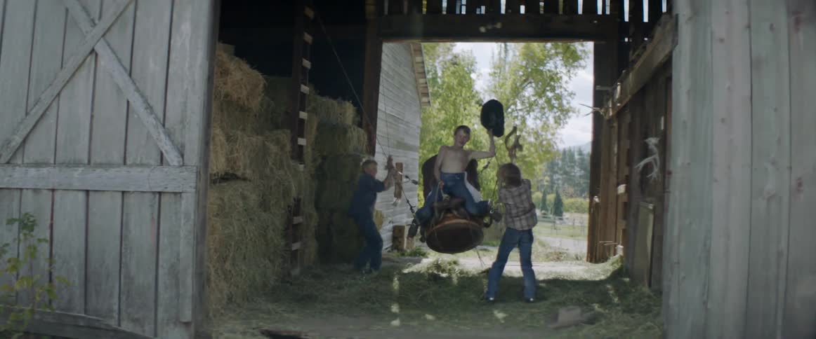 Kids are riding a fake bull in the barn