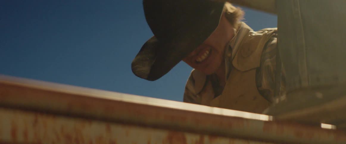 A man is tightening up ropes on a bull he is riding