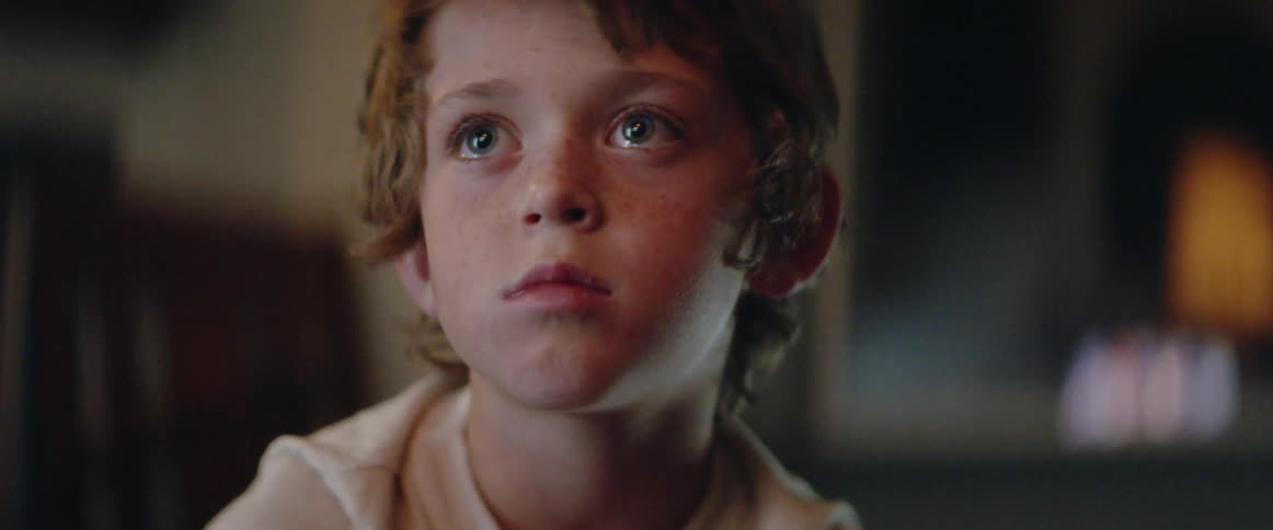 A young boy looks up at the television, caught by what he sees