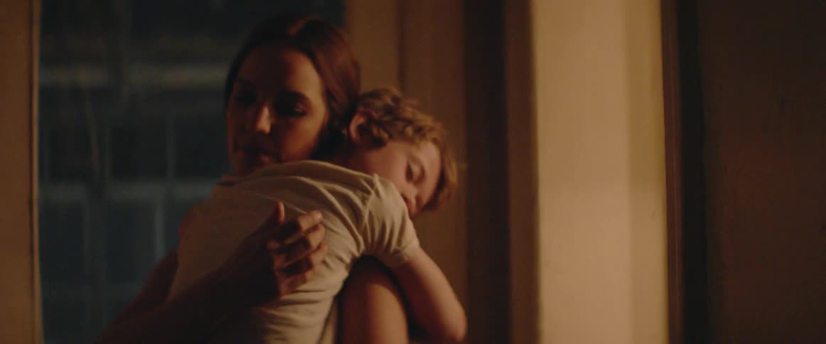 A mother gently carries her child through the quiet of night