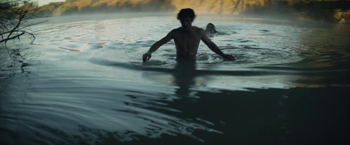 Two young men emerge from a misty river after a daring jump at dawn