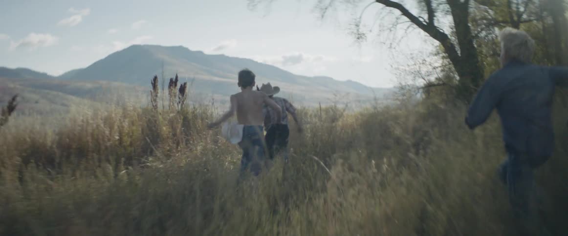 Boys runs across a rural field on a sunny day